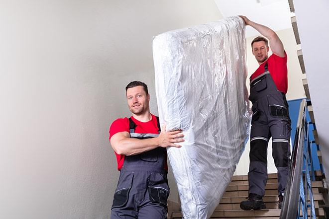 two workers carrying a heavy box spring out of a bedroom in Dolphin VA